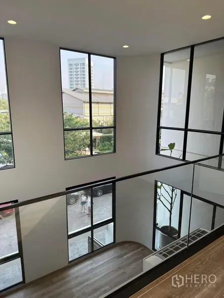 联排别墅 出租在Yan Nawa, Bangkok - 楼层过道配玻璃护栏，俯瞰挑高中庭与高窗