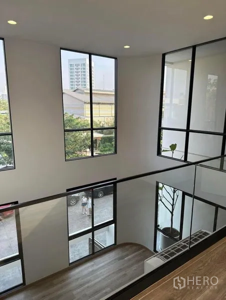 联排别墅 出租在Yan Nawa, Bangkok - 楼层过道配玻璃护栏，俯瞰挑高中庭与高窗
