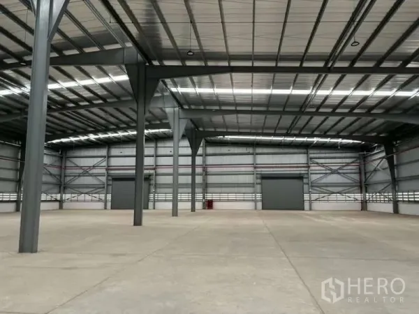 货栈 出租在Nikhom Phatthana, Rayong - 高挑钢结构仓库内部，抛光混凝土地面与大型卷闸门