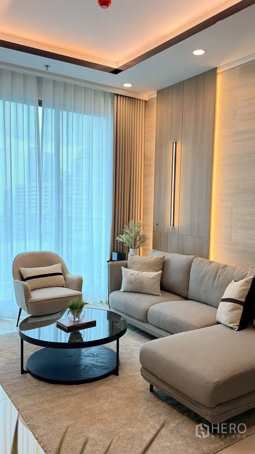 Condominium for rent in Watthana, Bangkok - Bright living room with an L-shaped sofa, armchair, and sheer curtains.
