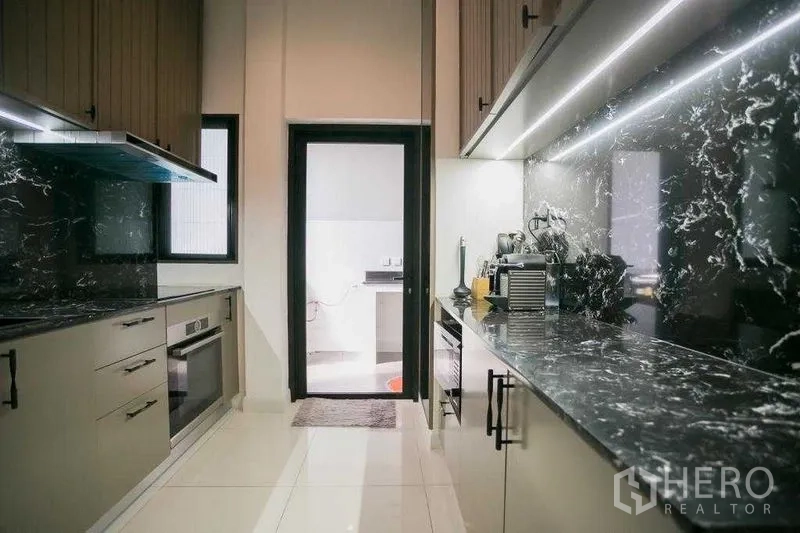 Detached House for rent in Bangkok - Full galley Thai kitchen with twin black marble countertops, under-cabinet lighting and door to utility.