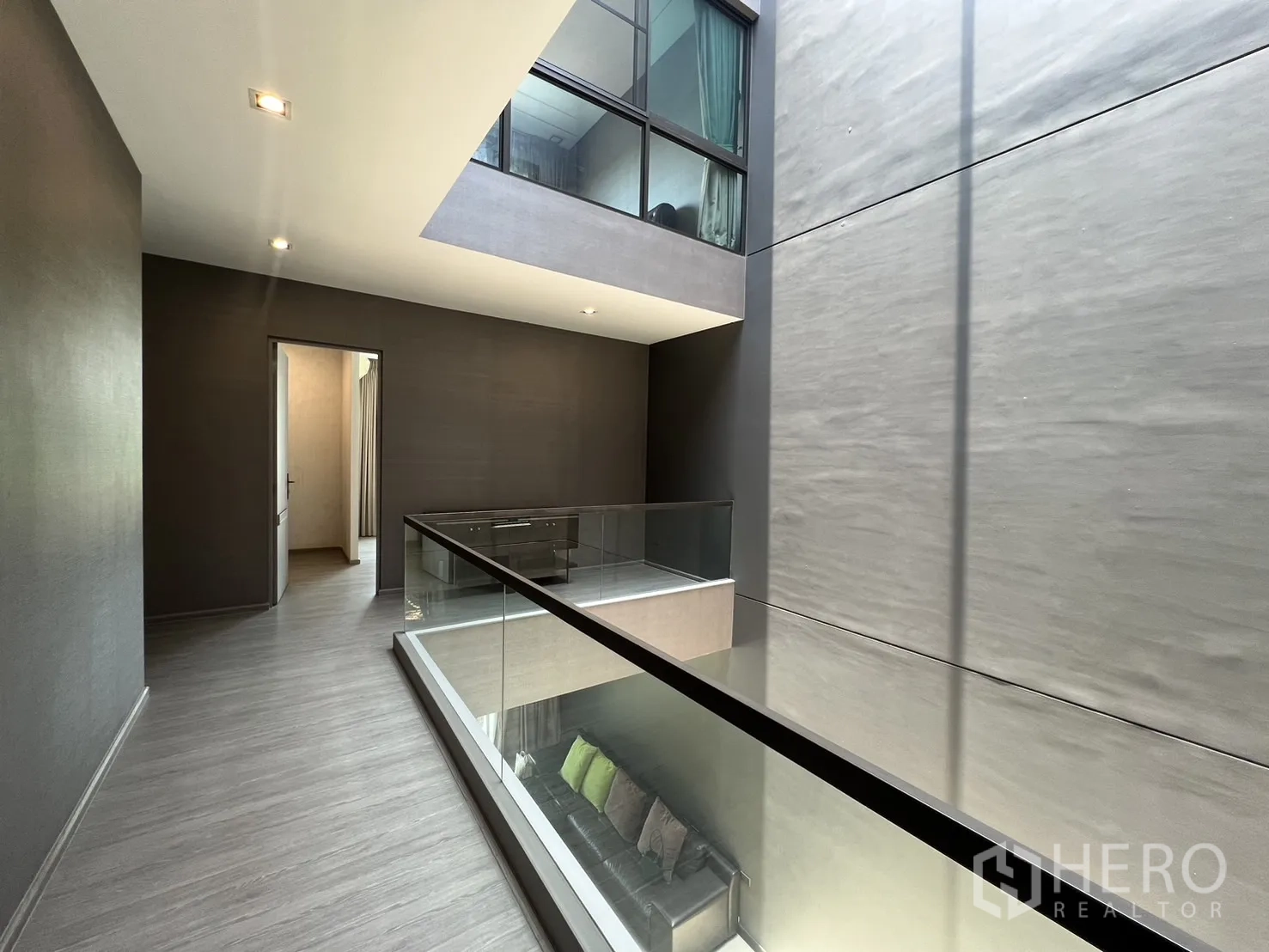 联排别墅 出租在Lat Phrao, Bangkok - 二層走道環繞中庭，玻璃欄杆與灰色地面。