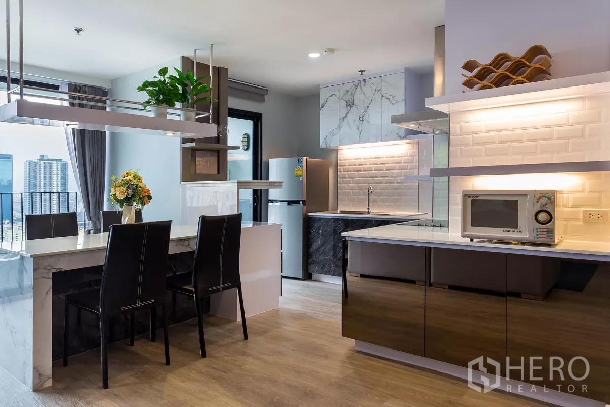Condominium for rent or sale in Watthana, Bangkok - Contemporary kitchen with dining island, hanging shelf with plants, refrigerator and city views.