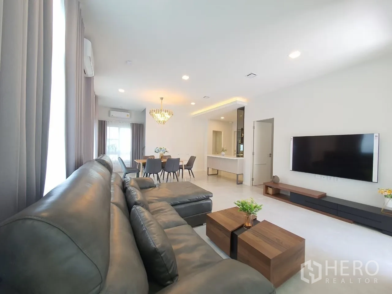 บ้าน ให้เช่าในPrawet, Bangkok - ห้องนั่งเล่นพร้อมโซฟาหนัง ทีวีติดผนัง และผ้าม่านสูงจรดเพดาน.