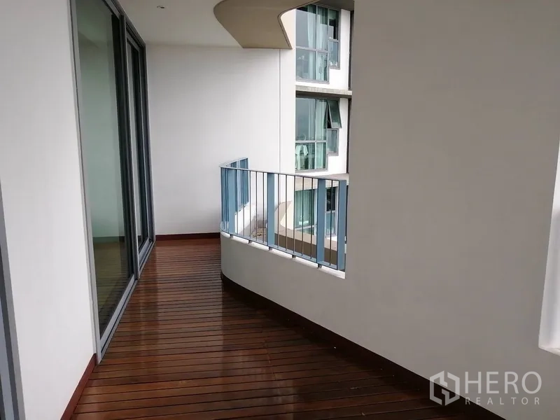 Condominium for sale in Yan Nawa, Bangkok - Curved wood-decked balcony with metal railing beside large glass sliders.