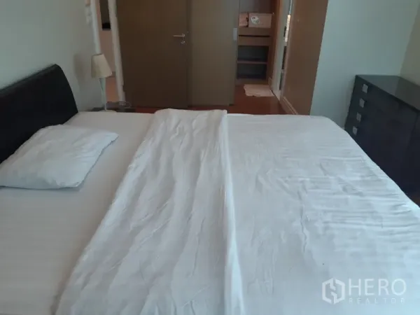 คอนโด ให้เช่าในKhlong Toei, Bangkok - มุมมองอีกด้านของห้องนอน แสดงเตียง ตู้ลิ้นชัก และประตูเข้าสู่ตู้เสื้อผ้าหรือห้องน้ำ