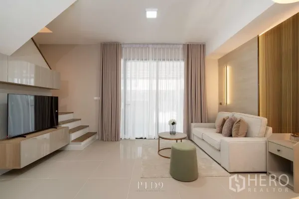 Townhouse for rent in Bang Phli, Samut Prakan - Cozy living room with sofa, coffee table and floor‑to‑ceiling sheer curtains