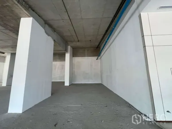 零售空间 出租 - 高挑毛坯商铺，白色墙面、裸露混凝土地面与立柱，适合二次装修