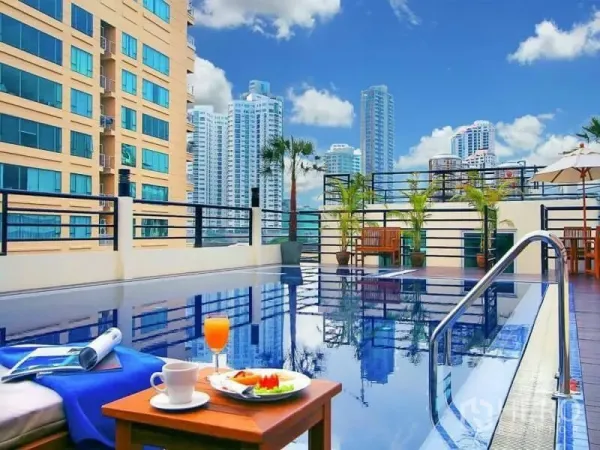 Apartment for sale in Ratchathewi, Bangkok - Rooftop swimming pool with city skyline views and seating area near Asok.