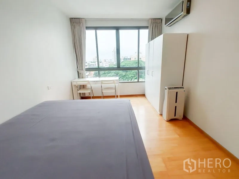 คอนโด ให้เช่าในKhlong Toei, Bangkok - ห้องนอนมีหน้าต่างบานใหญ่ โต๊ะทำงาน ตู้เสื้อผ้า มองเห็นวิวต้นไม้และเมือง