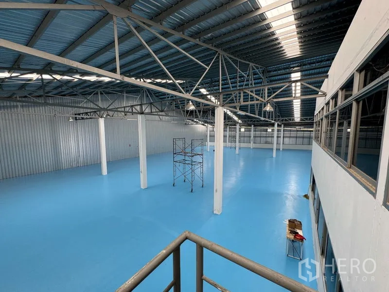货栈 出租在Mueang Pathum Thani, Pathum Thani - 室内开放空间，蓝色环氧地坪、钢桁架屋顶与采光带。