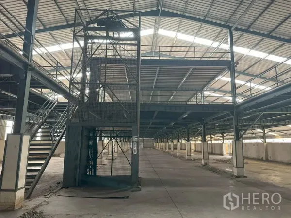 Factory for rent in Pathum Thani - Steel-frame factory interior with mezzanine levels and a freight lift under a high roof.