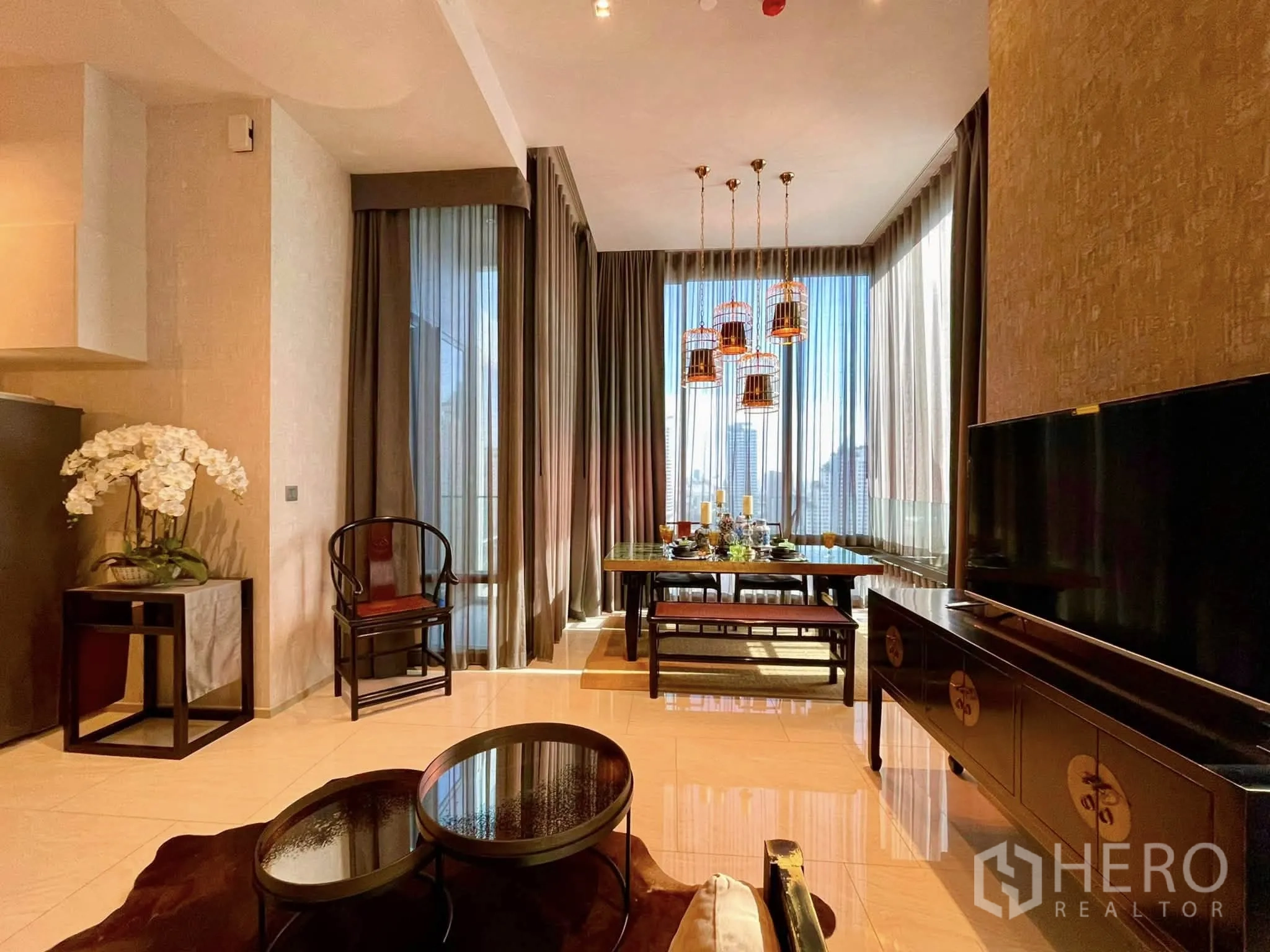 Condominium for rent in Bang Rak, Bangkok - Dining space with statement chandeliers, large windows and city backdrop.