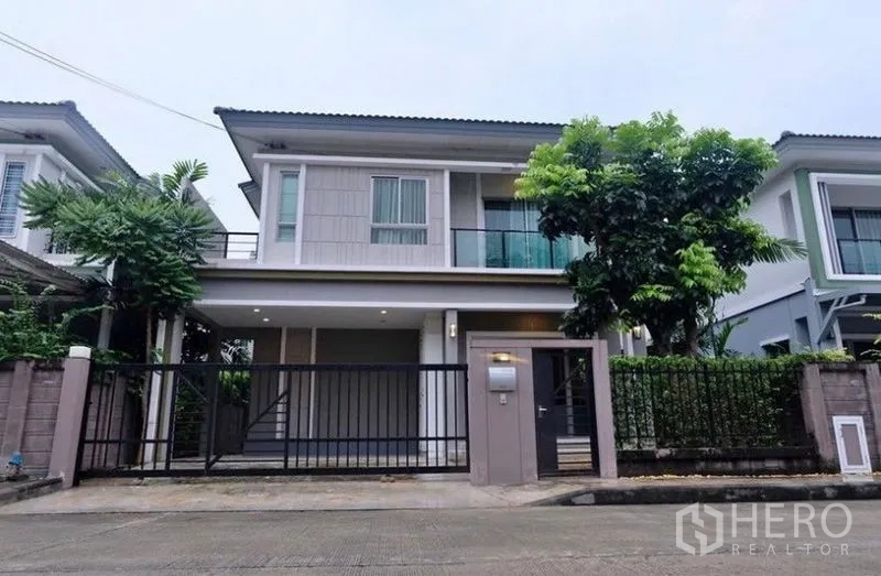 Detached House for rent in Suan Luang, Bangkok - Two-storey detached house exterior with gated carport, balcony, and mature tree in a quiet Suan Luang lane.