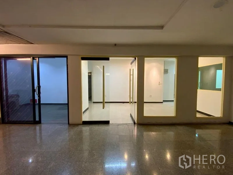 Office Space for rent in Watthana, Bangkok - Glass-fronted office entrance along a building corridor with sliding doors and display windows.