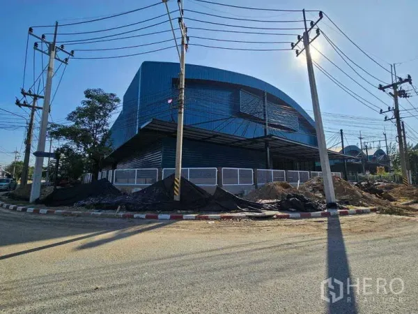 工厂 出租在Chon Buri - 蓝色厂房斜角外观，带雨棚装卸区和电线杆