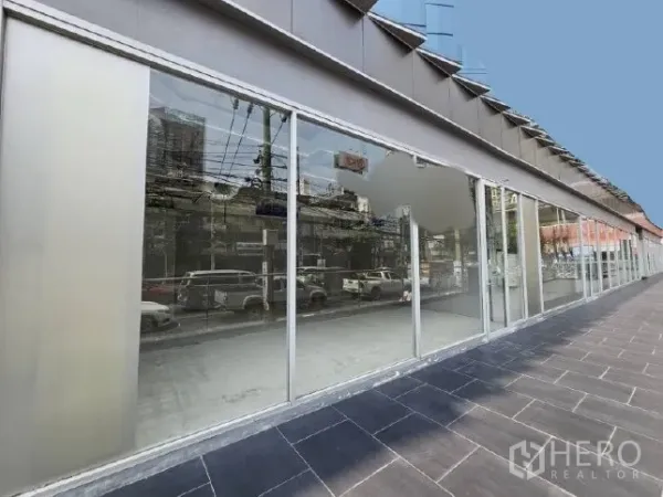 零售空间 出租 - 临街整面玻璃店面与宽人行道，映射周边街景与车流。