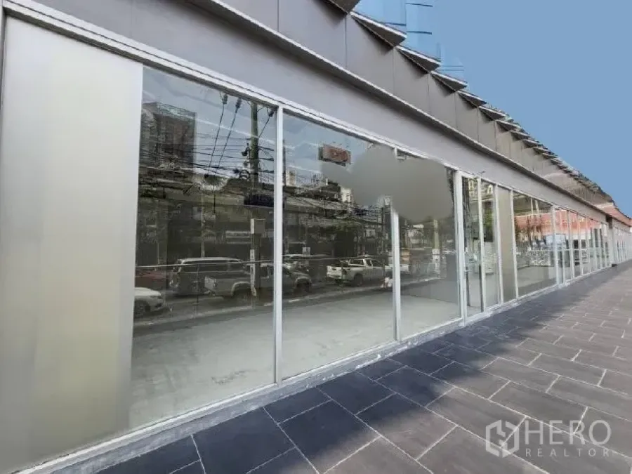 零售空间 出租 - 临街整面玻璃店面与宽人行道，映射周边街景与车流。