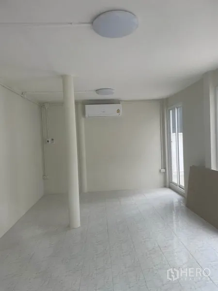 บ้าน ให้เช่าในHuai Khwang, Bangkok - ชั้นล่างแบบเปิดโล่ง ปูกระเบื้องสีขาว มีเครื่องปรับอากาศ และประตูกระจกออกลานบ้าน.