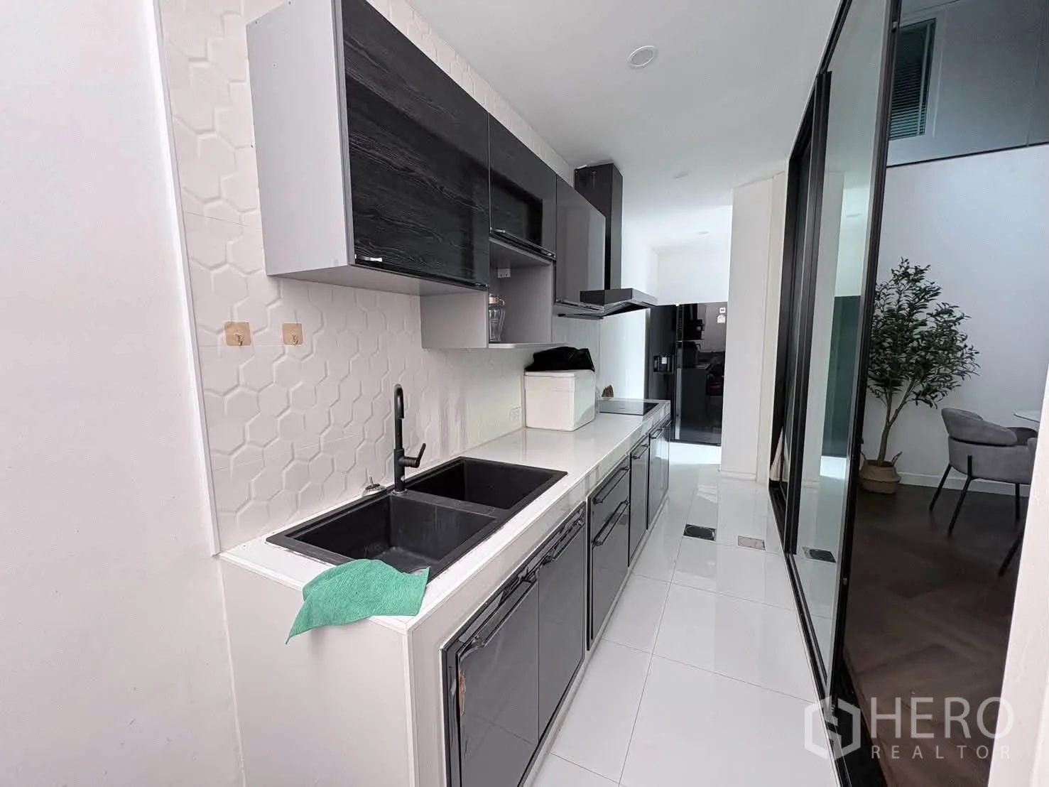 Detached House for rent in Saphan Sung, Bangkok - Sleek galley kitchen with black sink, cooktop, range hood, and glossy cabinets.