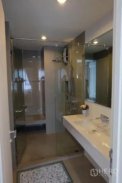 公寓 出租在Khlong Toei, Bangkok - 现代浴室，玻璃淋浴房与长台盆镜面柜。