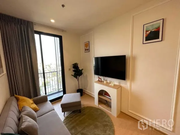 公寓 出售 - 温馨起居区，转角沙发、电视与俯瞰曼谷天际线的阳台。