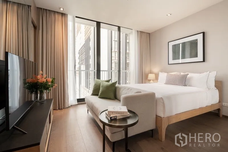 คอนโด ให้เช่า - ห้องนอนมีชั้นวางทีวี โซฟาปลายเตียง และประตูระเบียง