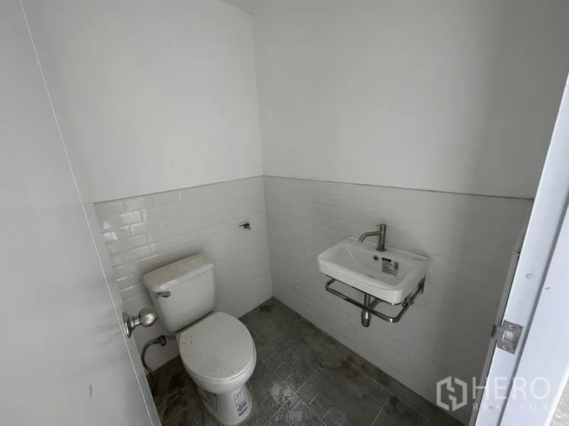 คลังสินค้า ให้เช่าในBang Phli, Samut Prakan - ห้องน้ำขนาดกะทัดรัด ผนังกระเบื้องสีขาว อ่างล้างมือแขวนผนังและโถสุขภัณฑ์ในโกดัง