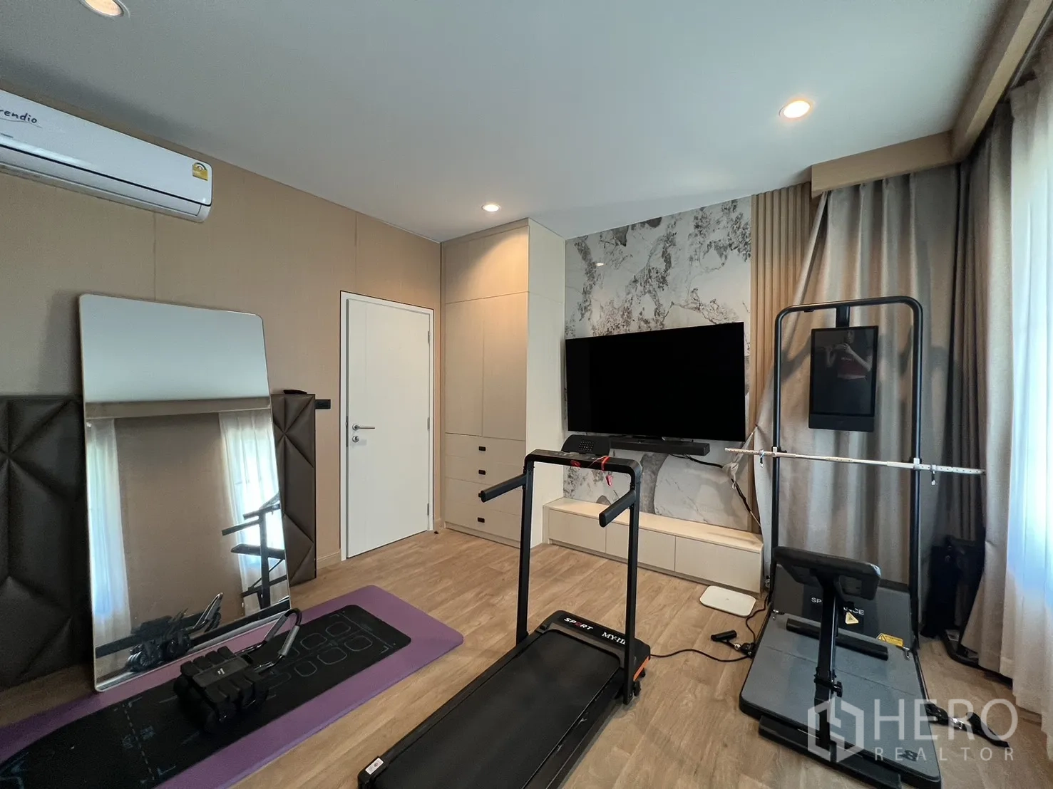 Detached House for rent or sale in Mueang Pathum Thani, Pathum Thani - Gym room angle with exercise equipment and wraparound curtains.