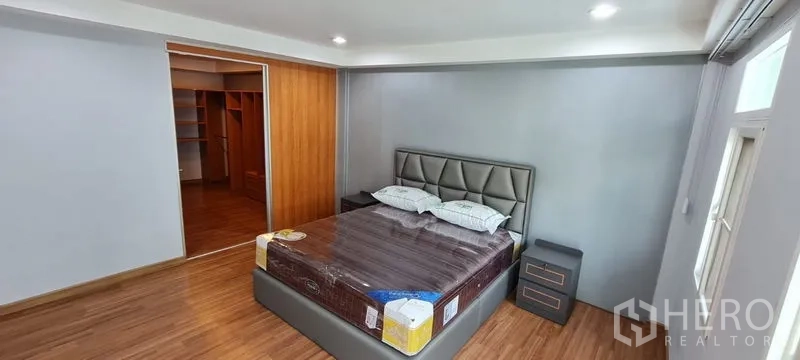 Townhouse for rent in Watthana, Bangkok - Primary bedroom connected to a walk-in closet with built-in shelving.