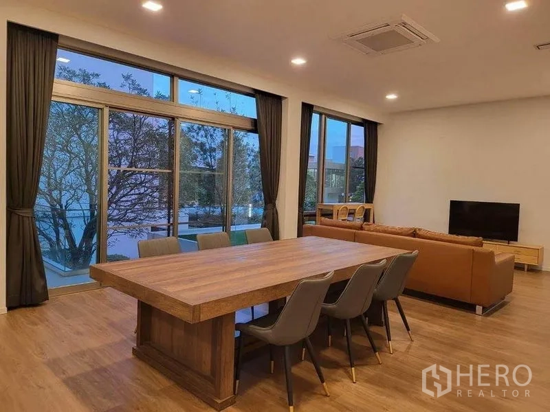 บ้าน ให้เช่าในSaphan Sung, Bangkok - โถงรับประทานอาหารและนั่งเล่นแบบโอเพ่นแพลน โต๊ะทานอาหารไม้ยาว โซฟาหนัง และประตูกระจกกว้าง