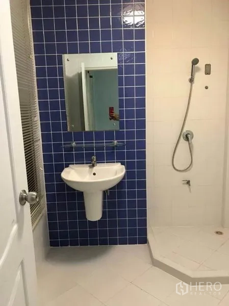联排别墅 出租在Wang Thonglang, Bangkok - 次卫，蓝色瓷砖墙、壁挂式台盆与淋浴区。