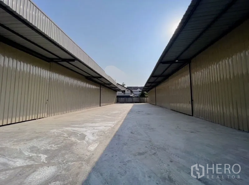 คลังสินค้า ให้เช่าในBang Na, Bangkok - ทางวิ่งคอนกรีตกว้างระหว่างโกดังสองฝั่ง พร้อมกันสาดยาวและประตูรั้วปลายทาง
