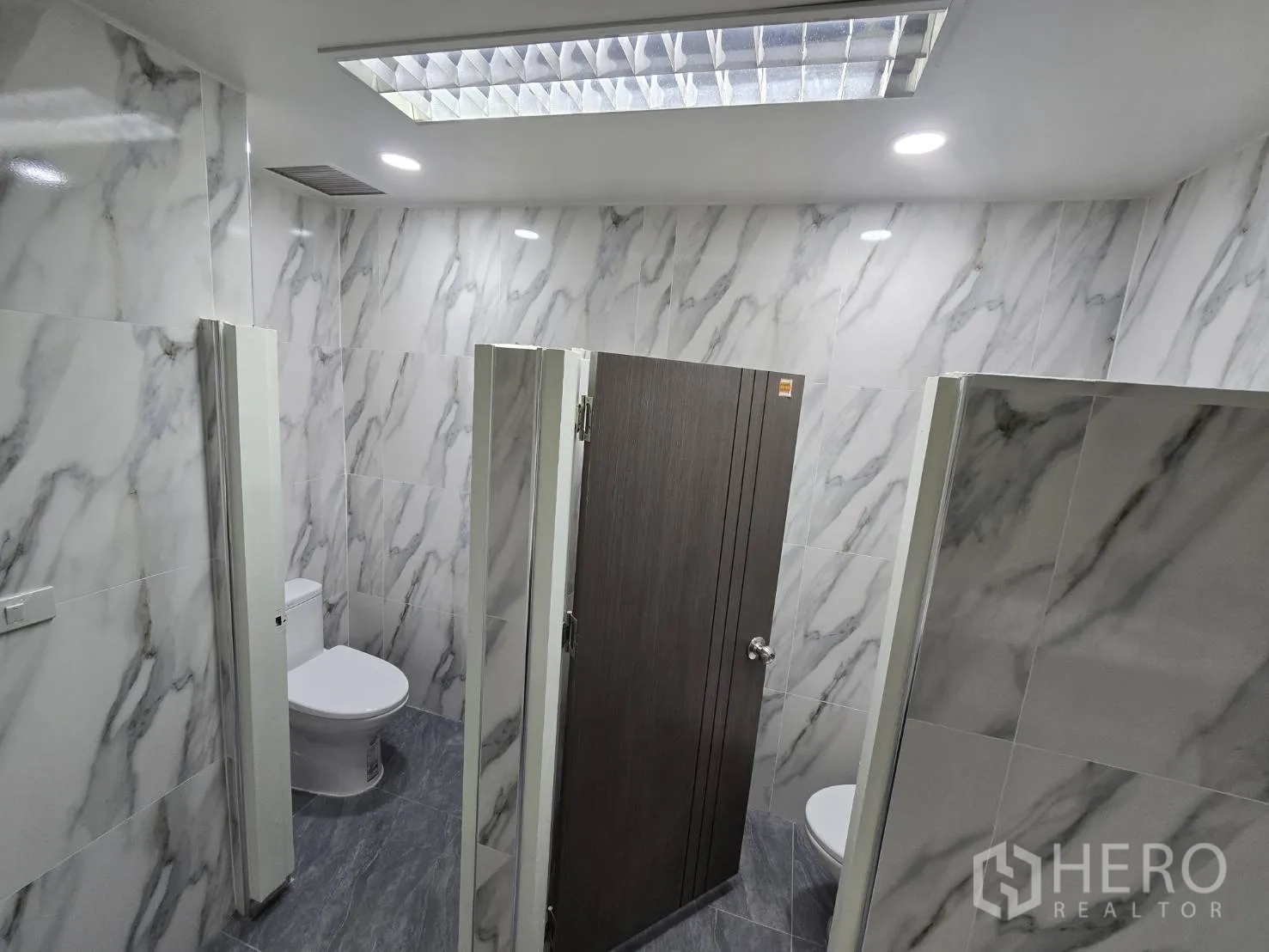 Office Space for rent in Khlong Toei, Bangkok - Restroom stalls with marble tiles and contemporary fixtures.