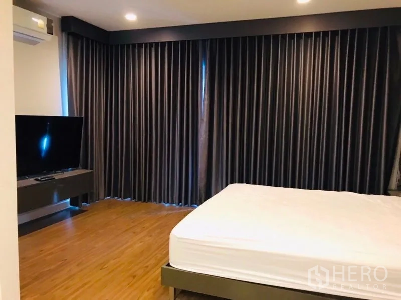 独立式住宅 出租或出售在Pathum Thani - 主卧木地板，床与遮光窗帘