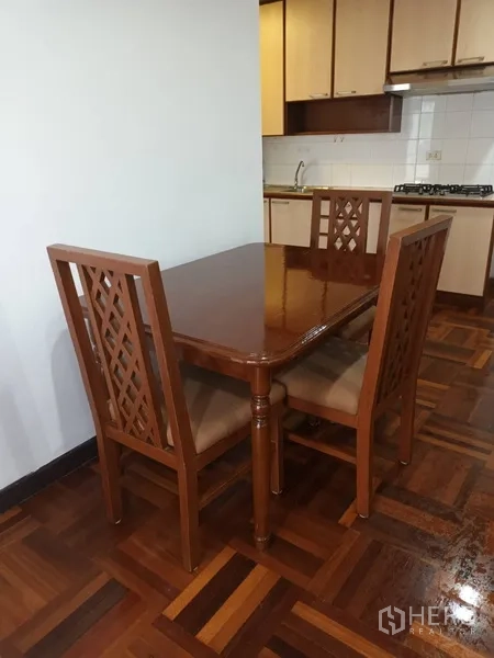 คอนโด ให้เช่าในDin Daeng, Bangkok - โต๊ะอาหารไม้พร้อมเก้าอี้พนักฉลุ ข้างทางเข้าครัว บนพื้นปาร์เกต์ขัดเงา