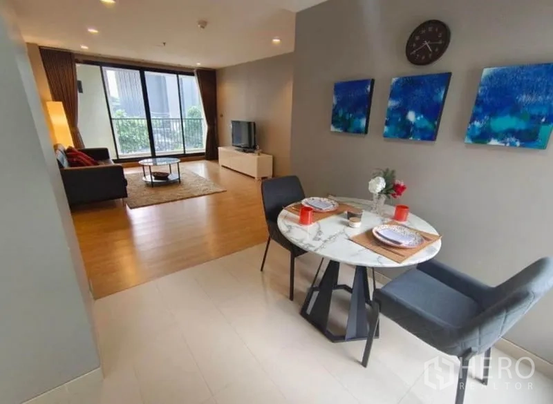 Condominium for rent in Watthana, Bangkok - Two‑seat dining area opens to a spacious living room with balcony and TV console.