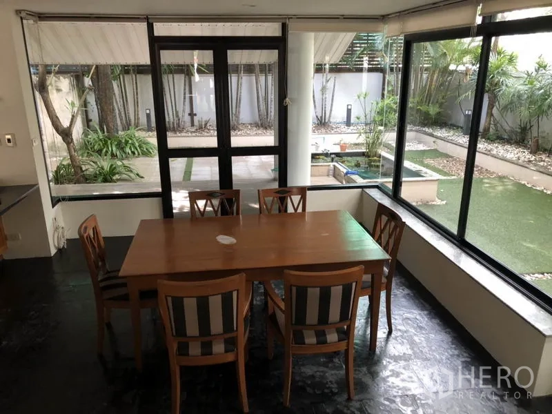 บ้าน ให้เช่าในBang Rak, Bangkok - พื้นที่รับประทานอาหารพร้อมเก้าอี้หกตัว รายล้อมด้วยหน้าต่างบานใหญ่เห็นลานสวน