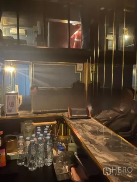 店屋 出租在Watthana, Bangkok - 大理石吧台与置物架、瓶装饮品，灯光柔和的吧区。