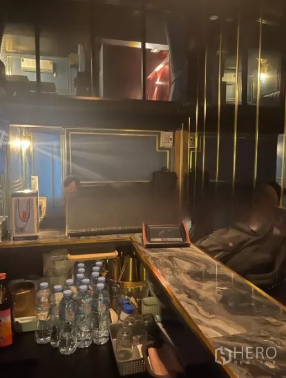 店屋 出租在Watthana, Bangkok - 大理石吧台与置物架、瓶装饮品，灯光柔和的吧区。