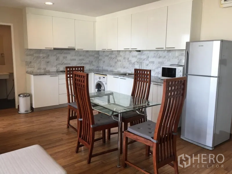 คอนโด ให้เช่าในWatthana, Bangkok - มุมทานอาหารโต๊ะกระจก เก้าอี้ไม้ และครัวครบพร้อมตู้เย็นในคอนโด