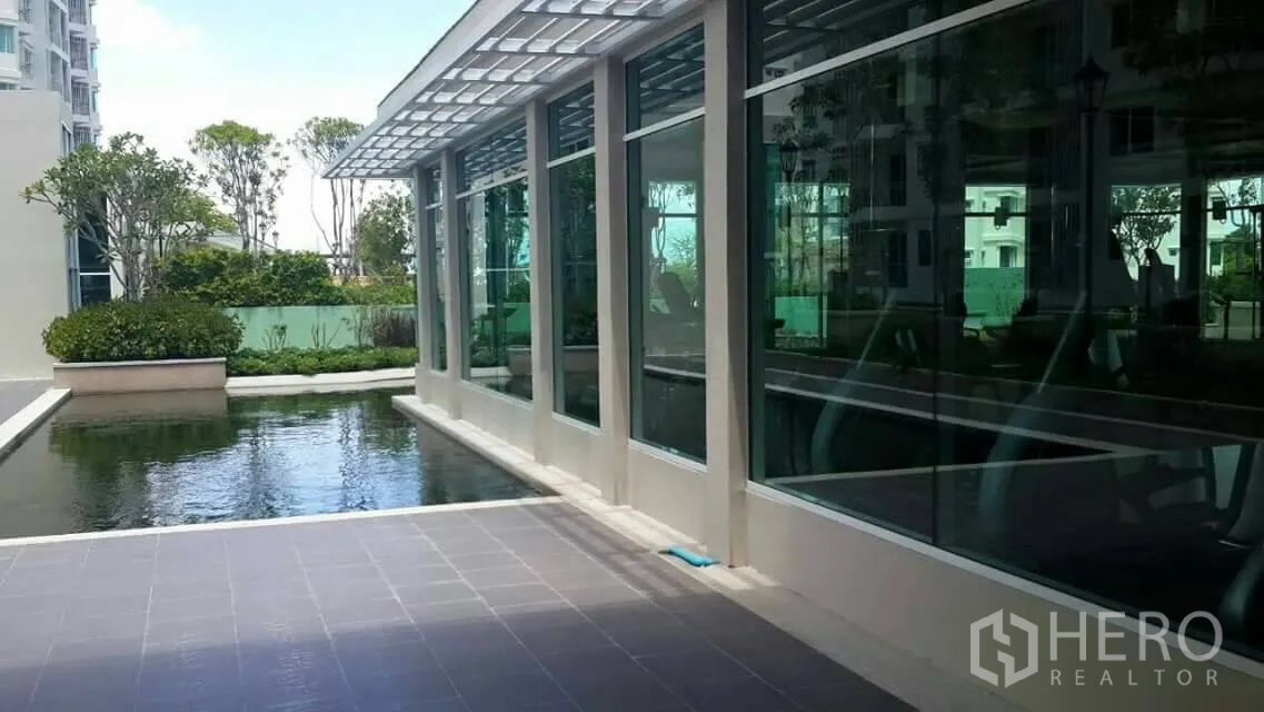 Condominium for sale in Huai Khwang, Bangkok - Glass-walled fitness center overlooking a reflecting pool and gardens.