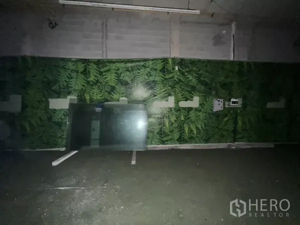 零售空间 出租 - 昏暗店铺内部，绿色墙板与悬挂式日光灯可见。