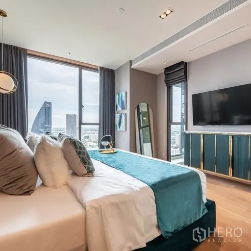 คอนโด ให้เช่าในKhlong Toei, Bangkok - ห้องนอนมาสเตอร์หัวเตียงกำมะหยี่สีเขียวเทอร์ควอยซ์ ทีวีติดผนัง และวิวสกายไลน์ผ่านกระจกเต็มบาน