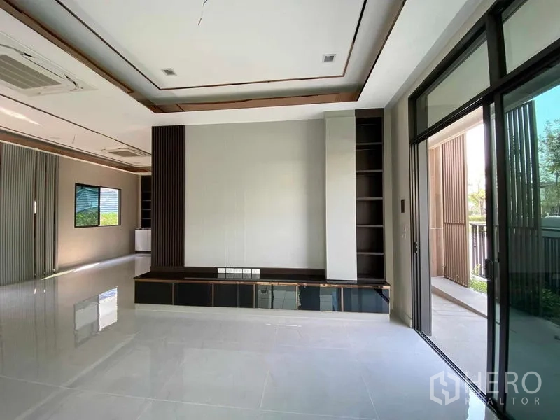 Detached House for sale in Don Mueang, Bangkok - Bright living area with built-in media wall, sliding glass doors and glossy tile flooring.