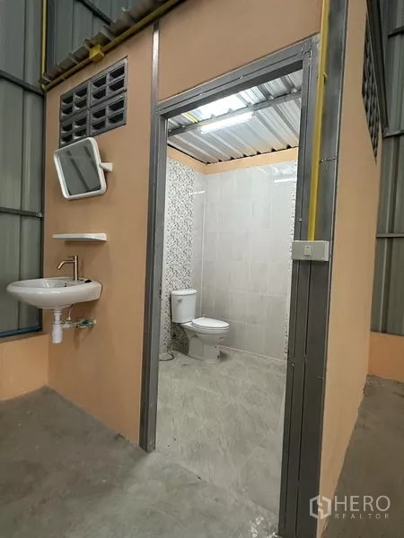 คลังสินค้า ให้เช่าในBueng Kum, Bangkok - ห้องน้ำส่วนตัวภายในโกดัง มีโถสุขภัณฑ์ อ่างล้างมือ และผนังปูกระเบื้อง