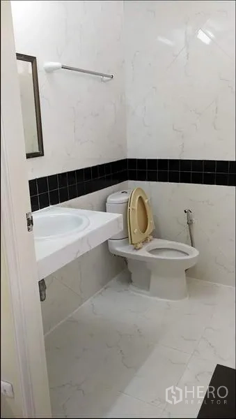 公寓 出租或出售在Khlong Toei, Bangkok - 整洁卫浴，白色仿大理石瓷砖，黑色装饰带，洗手台与坐便器。