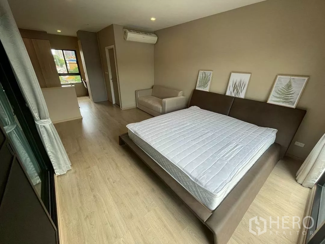 ทาวน์เฮาส์ ให้เช่าในSuan Luang, Bangkok - มุมมองอีกด้านของห้องมาสเตอร์ แสดงพื้นที่นอน โซฟา มุมนั่งทำงาน และประตูห้องน้ำในตัว.