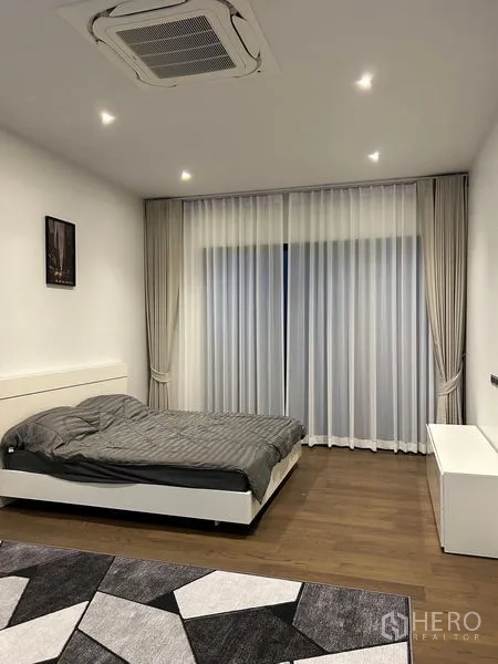 Detached House for rent in Bang Kapi, Bangkok - Spacious bedroom with gray bedding, recessed lights and sheer drapes