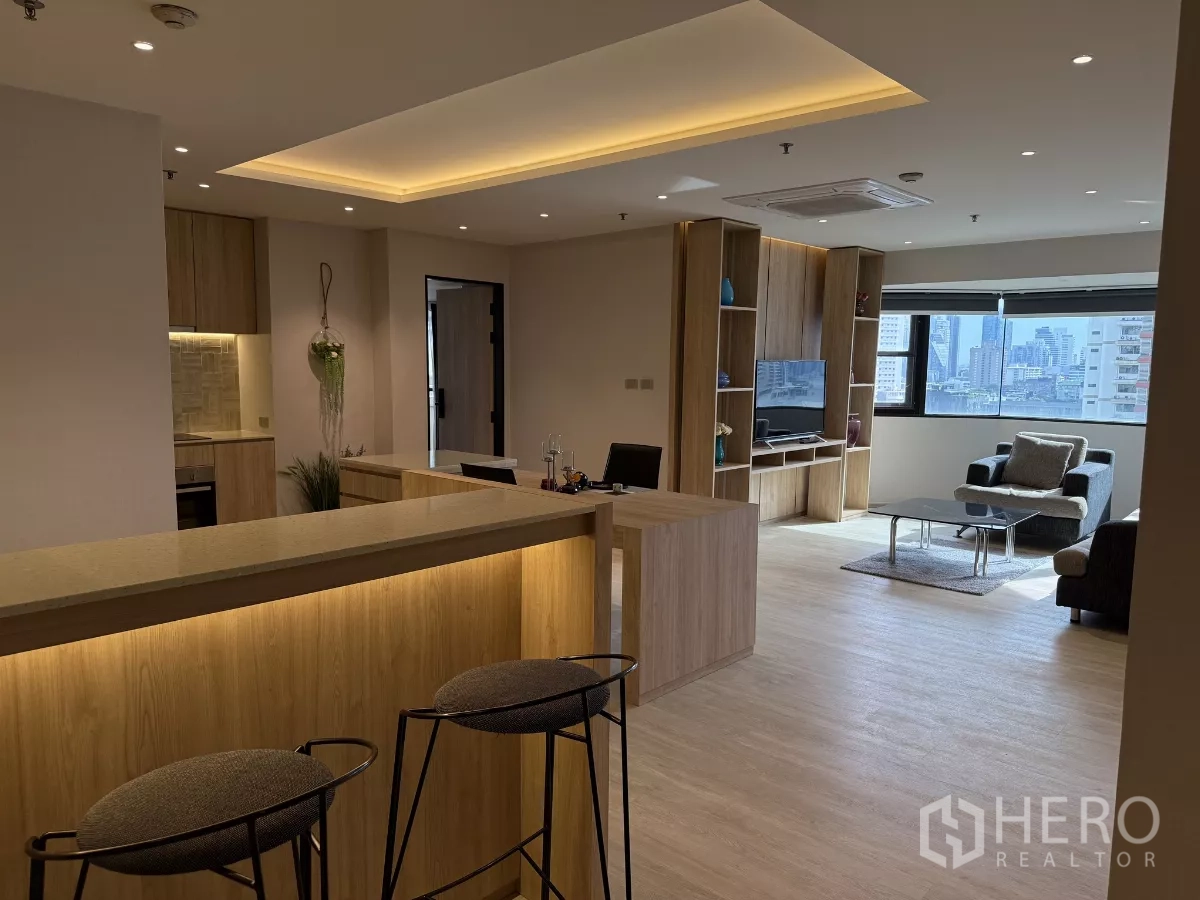 คอนโด ให้เช่าในWatthana, Bangkok - พื้นที่นั่งเล่นแบบโอเพ่นพร้อมเคาน์เตอร์บาร์ไม้ ชั้นวางทีวีบิวท์อิน โซฟา และหน้าต่างบานกว้างวิวเมือง.